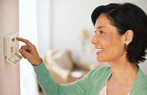 Woman adjusting thermostat