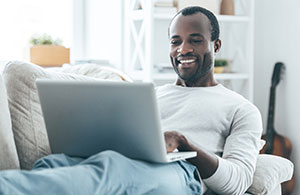 Man laying on sofa looking at laptop 